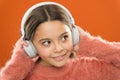 Girl cute little child wear headphones listen music. Kid listen music orange background. Recommended music based on Royalty Free Stock Photo