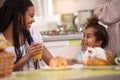 Girl with little sister at the table having breakfast Royalty Free Stock Photo