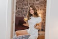 Girl with cute smile enjoying orange juice while listening music on couch. Indoor portrait of glad beautiful lady in