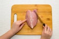 Girl cuts chicken fillet on a wooden Board. Women`s hands, wooden Board, knife. Top view Royalty Free Stock Photo