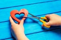 Girl cuts the heart with scissors, the concept of breaking relations, quarrels and divorce. Betrayal of the othere. blue backgroun Royalty Free Stock Photo