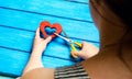 Girl cuts the heart with scissors, the concept of breaking relations, quarrels and divorce. Betrayal of the othere. blue backgroun Royalty Free Stock Photo