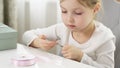 A girl cuts a pink ribbon for gift wrapping with scissors.