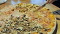 The girl cuts pizza with ham and mushrooms. Hands close-up.