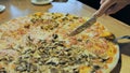 The girl cuts pizza with ham and mushrooms. Hands close-up.