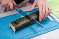 The girl cuts the ready-made sushi in half with a sharp kitchen knife Royalty Free Stock Photo