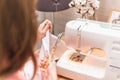 A girl cuts a thread from a stitched product. A beautiful seamstress works at a sewing machine Royalty Free Stock Photo
