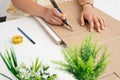 Girl cutting cardboard with a cutter on a thick white surface near the house plants Royalty Free Stock Photo