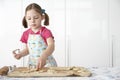 Girl (5-6) cutting dough on board in kitchen