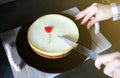 Girl is cutting with a knife classical vanilla New York cheesecake on dark-violet plate on wooden tray with rope handles. Small re Royalty Free Stock Photo