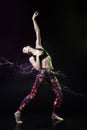 The girl dances on the floor covered with water on a black background and water splashes around her Royalty Free Stock Photo