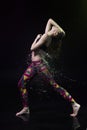 The girl dances on the floor covered with water on a black background and water splashes around her Royalty Free Stock Photo