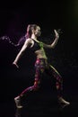 The girl dances on the floor covered with water on a black background and water splashes around her Royalty Free Stock Photo