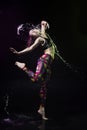 The girl dances on the floor covered with water on a black background and water splashes around her Royalty Free Stock Photo