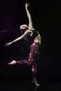 The girl dances on the floor covered with water on a black background and water splashes around her Royalty Free Stock Photo