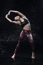 The girl dances on the floor covered with water on a black background and water splashes around her Royalty Free Stock Photo