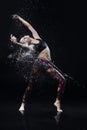 The girl dances on the floor covered with water on a black background and water splashes around her Royalty Free Stock Photo