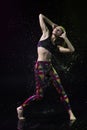 The girl dances on the floor covered with water on a black background and water splashes around her Royalty Free Stock Photo