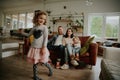 Cute girl dancing with parents and younger sister watching sitting on couch at home Royalty Free Stock Photo