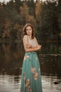 A girl is dancing on a wooden bridge against the backdrop of a forest lake. Royalty Free Stock Photo