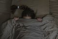 Girl with dark hair hides in bed with fear Royalty Free Stock Photo