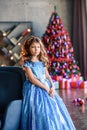 Girl with dark hair standing on a box with gifts. Christmas tree in the background. smiles Royalty Free Stock Photo