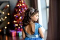 Girl with dark hair standing on a box with gifts. Christmas tree in the background. smiles Royalty Free Stock Photo