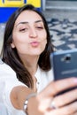 Girl with dark hair and white shirt taking a selfie and doing a funny face