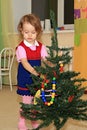 Girl decorates a conifer.