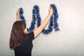 The girl decorates the wall with a blue tinsel