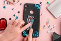 Girl decorating a black phone case with rhinestones and embroidered patches
