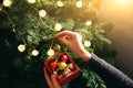 Girl is decorating christmas tree with lights. Present box with toys in woman`s hands. Love and holidays concept. New Year mood. Royalty Free Stock Photo