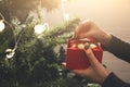 Girl is decorating christmas tree with lights. Present box with toys in woman`s hands. Love and holidays concept. New Year mood. Royalty Free Stock Photo