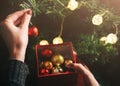 Girl is decorating christmas tree with lights. Present box with toys in woman`s hands. Love and holidays concept. New Year mood. Royalty Free Stock Photo