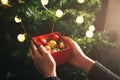 Girl is decorating christmas tree with lights. Present box with toys in woman`s hands. Love and holidays concept. New Year mood. Royalty Free Stock Photo