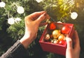 Girl is decorating christmas tree with lights. Present box with toys in woman`s hands. Love and holidays concept. New Year mood. Royalty Free Stock Photo