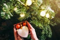 Girl is decorating christmas tree with lights. Present box with toys in woman`s hands. White fluffy heart. Love and holidays Royalty Free Stock Photo