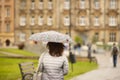 A girl in a denim blue jacket with a white transparent umbrella walks in the rain among the green. Romantic mood. Melancholic wet