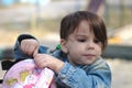 A girl in a denim jacket with a tail looking in a backpack on the playground Royalty Free Stock Photo