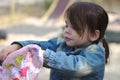 A girl in a denim jacket with a tail looking in a backpack on the playground