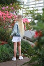 Girl in a denim jacket walks in the garden with blooming azalea
