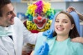 Girl in dental clinic with dentist and clown in background