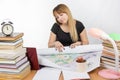 Girl design student sitting at desk and is tired deploys a large drawing