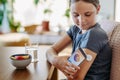 Girl with diabetes checking blood glucose level at home using continuous glucose monitor. Schoolgirl connecting CGM to