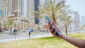 The girl dials a number or message on the smartphone against the backdrop of the city streets of Dubai. Hands close-up. Royalty Free Stock Photo