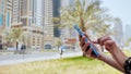 The girl dials a number or message on the smartphone against the backdrop of the city streets of Dubai. Hands close-up. Royalty Free Stock Photo