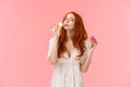 Girl on diet cant resist temptation eating sweets. Alluring funny and cute redhead female holding two tasty macarons