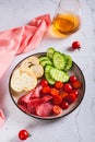 Girl dinner of smoked meats, vegetables and bread on a plate on the table vertical view