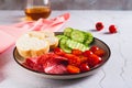 Girl dinner of smoked sausage, cucumbers, cherry tomatoes and buns on a plate on the table