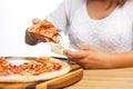 A girl dips a slice of pizza in sauce